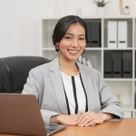 An Asian businesswoman sitting at a desk with a laptop, focused on her work