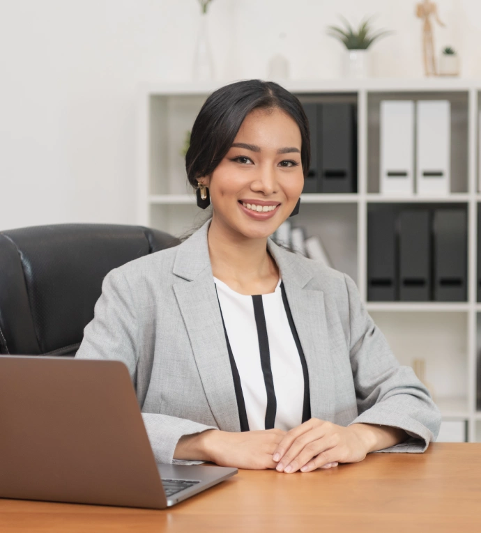 An Asian businesswoman sitting at a desk with a laptop, focused on her work