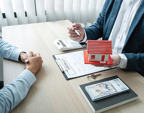 A mortgage lender showing a house model to a client in an office setting