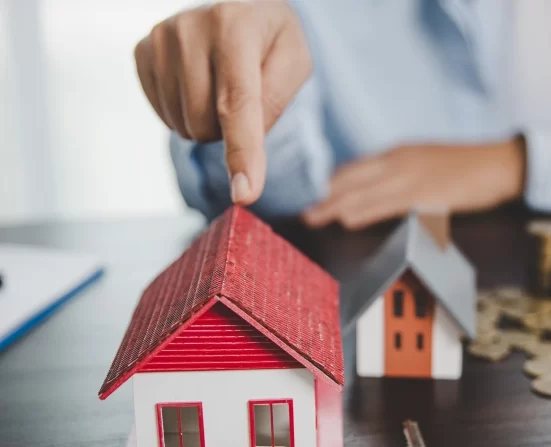 Alt A person pointing to a miniature model of a house