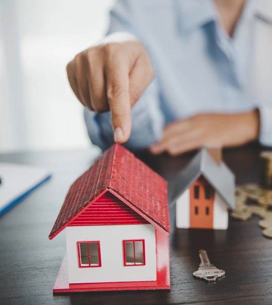 Alt A person pointing to a miniature model of a house