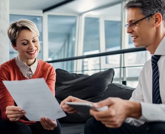 Alt A businessman and woman sitting on a couch, reviewing paperwork together.