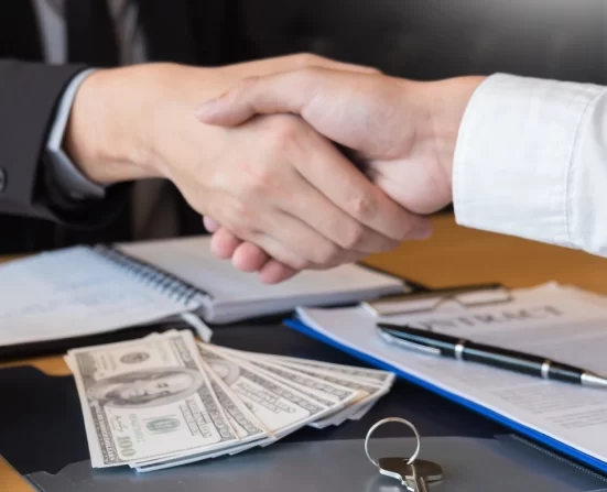 Alt A handshake over a document with a bunch of dollar bills