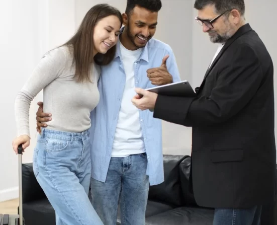 Alt A man and woman moving into a house, with the mortgage lender holding a document.