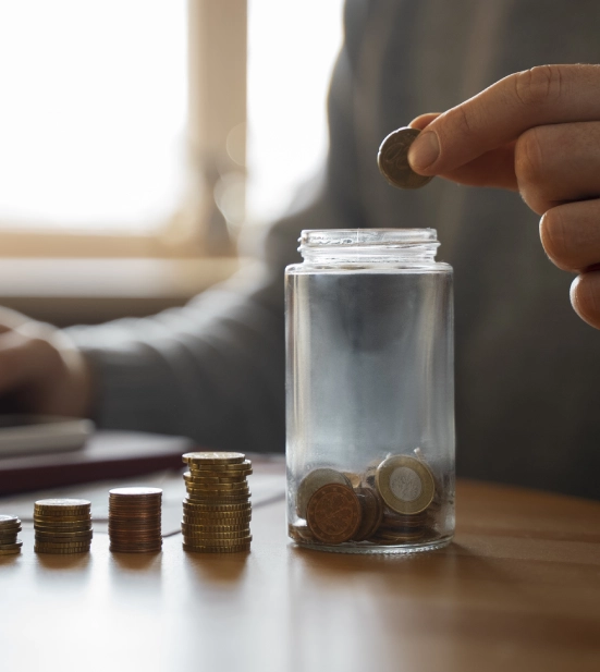 A person storing coins in a glass bottle